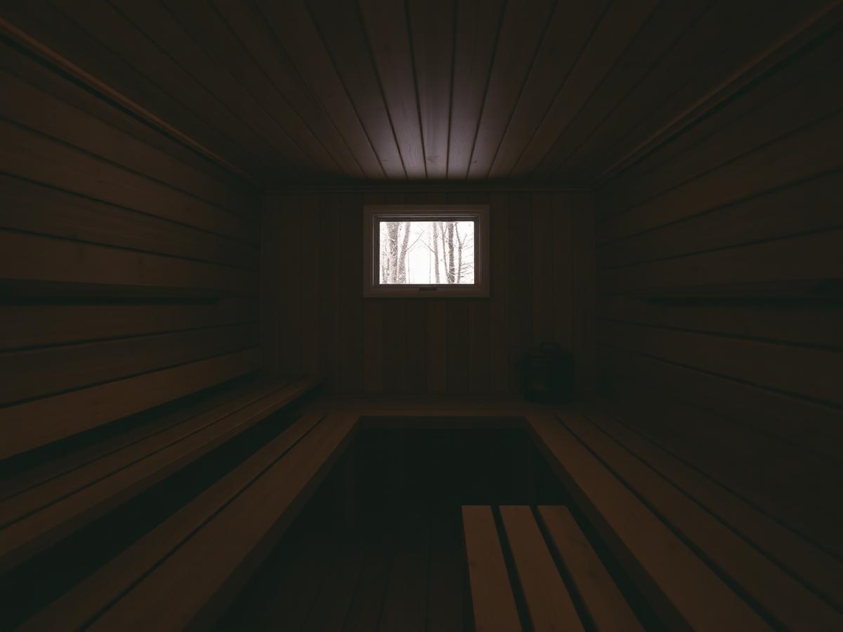 Sauna aus Lärchenholz mit Fenster zum Winterwald